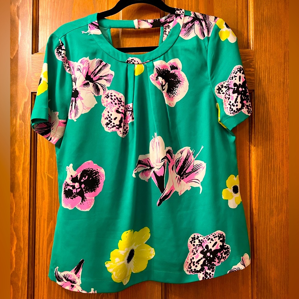 Short sleeved tropical print with cute cut out drape on back. Wash & wear.